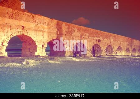 Aquädukt in der antiken Stadt Caesarea bei Sonnenuntergang. Kreative Farben Stockfoto