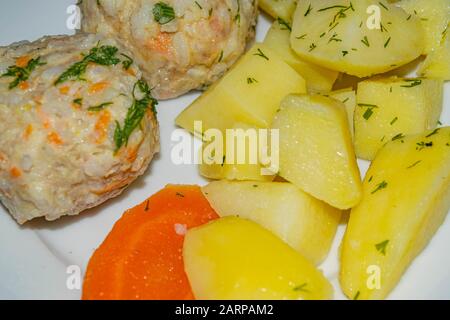 Fleischfleischbällchen mit gekochten Kartoffeln und gekochten Karotten auf einem weißen Teller. Nahaufnahme Stockfoto