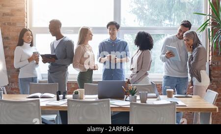 Eine Gruppe von multirassischen Jugendlichen, die während des Kaffeebruchs sprechen Stockfoto