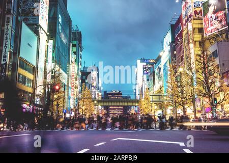 Tokio, JAPAN - 06.01.2016: Die belebte Hauptstraße in Akihabara Electric Town im Winter. Massen verschwommener Menschen, die die Straße überqueren, helle Schilder Stockfoto