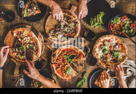 Menschen, die verschiedene Arten von Pizza und Wein essen Stockfoto