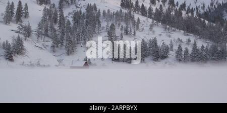 Eine Scheune, die sich im Nebel am frühen Morgen in einer schneebedeckten Weide in Beavertail, Montana im Granite County verhüllt hat. Stockfoto