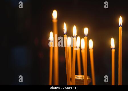 Kerzen in der orthodoxen Kirche auf Zypern. Dunkelheit ringsum. Weicher Fokus. Symbole im Hintergrund Stockfoto