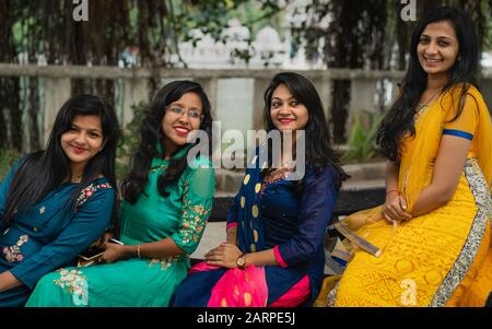 Gruppe von vier schönen, lächelnden Frauen in traditioneller Kleidung, die auf der Bank in Udaipur, Rajasthan, Indien sitzen. Stockfoto