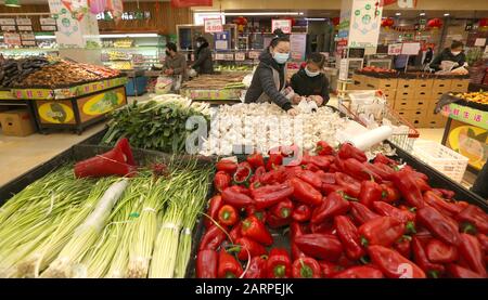 Chinesische Kunden, die Gesichtsmasken zur Vorbeugung des neuen Coronavirus und Pneumonie tragen, kaufen während des chinesischen New Y in einem Supermarkt Gemüse ein Stockfoto