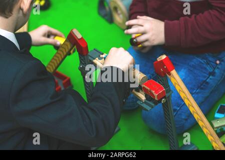 Kinder sammeln Spielzeugeisenbahn. Designerartikel aus Holz in Kinderkrebsen. Stockfoto