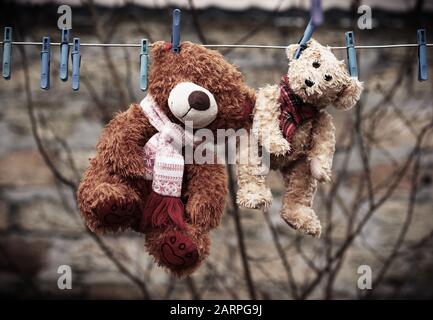 Süße braune, nasse Teddybären hängen an einer Wäscheleine und trocknen in der frischen Luft, Vintage-Tönung Stockfoto