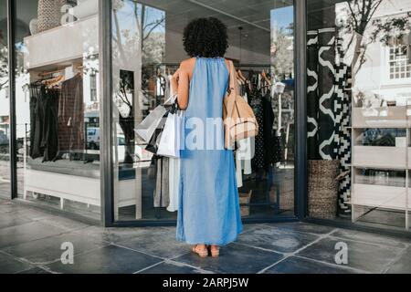 Frau, die beim Einkaufen von Kleidung auf eine Schaufensteranzeige schaut Stockfoto