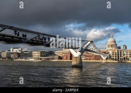 London - 28. JANUAR: Fußgänger überqueren die Millennium Bridge in London im Wintersonnenlicht, das auf die Kuppel der St. Paul's Cathedral scheint, während zwei Schwäne an der Themse vorbeiziehen. Foto: © 2020 David Levenson Stockfoto