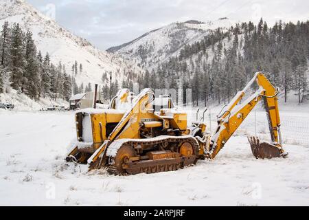 Ein schneebedeckter John Deere-Baggerlader Modell 2010 mit Diesellader auf einem Bauernhof in Beavertail, Montana Stockfoto