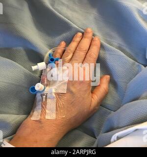 Ein Patient mit Infusionstropfen wartet bei einer englischen NHS-Bettenoperation Stockfoto