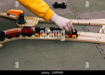 Spielzeugeisenbahn. Kinderhand treibt einen Spielzeug-Holzzug an. Ein spannendes Spiel für Kinder im Kindergarten oder in der Schule. Stockfoto