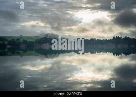 Wolken- und Nebelschwaden bei Sonnenaufgang nach einem Sturmzug über die Illasschlucht am Forggensee, im Allgäuer, Bayern, Deutschland Stockfoto