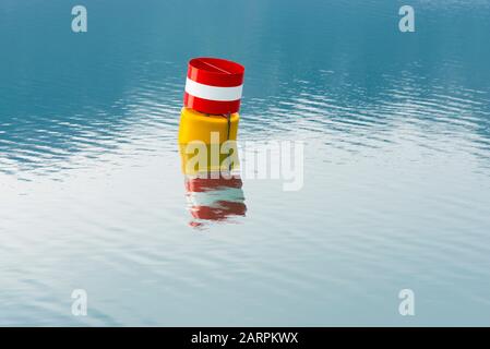 Gelbe Boje für verstopfte Wasseroberfläche mit rotem und weißem Oberschild zum vorbeiziehen, ohne die Geschwindigkeit auf der freien Seite eines Sees zu verringern Stockfoto