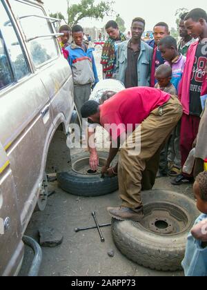 Die Äthiopier vor Ort schauen neugierig auf die Reparatur des Hinterrades in einem Jeep. Äthiopien. Stockfoto