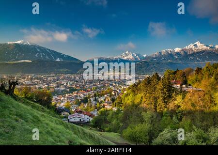 Blick auf das Zentrum von Innsbruck im unteren Inntal, vom Gasthof Olberg an der Hohenstraße, bei Sonnenaufgang, großes Loffler-Massiv in Zillertaler Alpen in der Ferne, Stockfoto