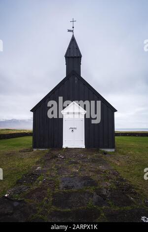 Búðakirkja, die schwarze Küstenkirche von Island, an der Südküste der Halbinsel Snaefellsnes auf Island. Atemberaubende weiße Tür und epische Überwurf Stockfoto