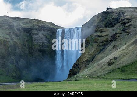 Der Wasserfall Skógafoss, der an einem bewölkten Tag in Island an der berühmten Ringstraße mit großer Kraft fließt. Der Wasserfall ist einer der erstaunlichsten Ort Stockfoto