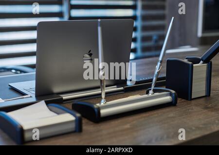 Moderner Büroarbeitsplatz. Business-Laptop am Arbeitsplatz für Chef, Chef oder andere Mitarbeiter. Notizbuch auf Arbeitstisch. Licht durch halb geöffnete Jalousien - 20 Stockfoto