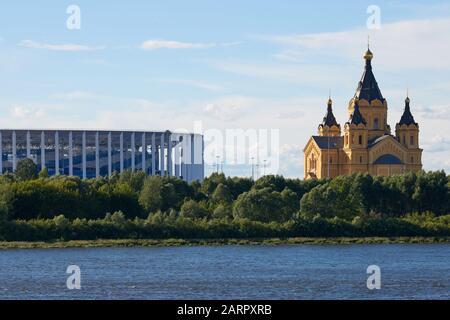 Russland, Nischny Nowogorod - 07.07.2019 - Stadion und orthodoxe Kirche in der Nähe des Flusses. Stadion für Fußball-Weltmeisterschaft. Spit von Nischni Nowgorod Stockfoto