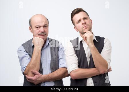 Ernst zwei kaukasische Männer halten die Zügel tief in Gedanken, finden den Weg aus dem Problem heraus. Familienproblemkonzept. Studio gedreht Stockfoto