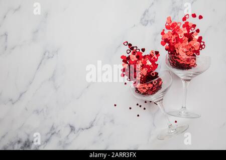 Champagnerglas überströmt mit rotem Valentinskerz Herzconfetti Stockfoto