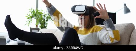 Frau sitzt zu Hause auf der Couch verwendet virtuelle Realität Stockfoto