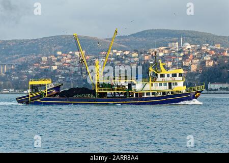 Kommerzielles Fischerboot vom Typ Trawler, das durch die Bosporus-Straße in Istanbul segelt. Ein großes Rettungsboot hing auf dem Rücken und Möwen flogen. Stockfoto