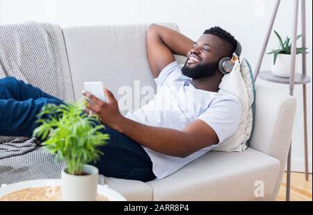 Schwarzer Mann in Kopfhörer ansehen Film auf dem Smartphone Stockfoto