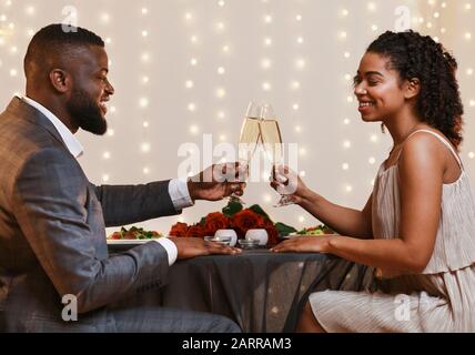 Fröhliches Afro Paar, das festliches Abendessen im schicken Restaurant hat Stockfoto