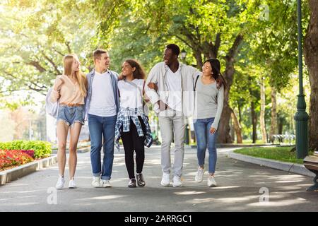 Studenten, die nach der Universität im Park spazieren, plaudern und Spaß haben Stockfoto