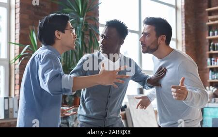 Multirassische Kollegen, die Streit im Amt haben, Interessenkonflikt Stockfoto