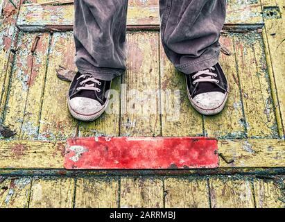 Beine eines Mannes in alten schmutzigen Schuhen auf einem gelben Holzboden dicht oben Stockfoto