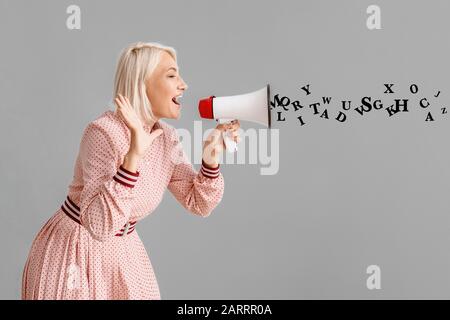 Sprachschullehrer mittleren Alters mit Megafon auf grauem Hintergrund Stockfoto