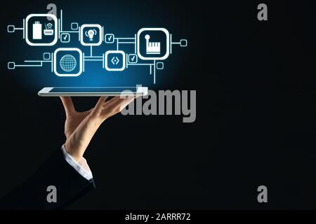 Geschäftsfrau hält Tablet-PC mit digitalen Symbolen auf dunklem Hintergrund. Konzept der Geschäftsplanung Stockfoto