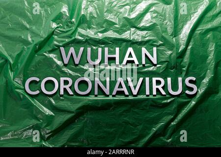 Wörter wuhan coronavirus gelegt mit Metallbuchstaben auf zerknittertem Grün Kunststoff-Folie Hintergrund - flach legen mit Komposition Stockfoto