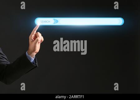 Geschäftsmann mit Web-Suchmaschine vor dunklem Hintergrund Stockfoto