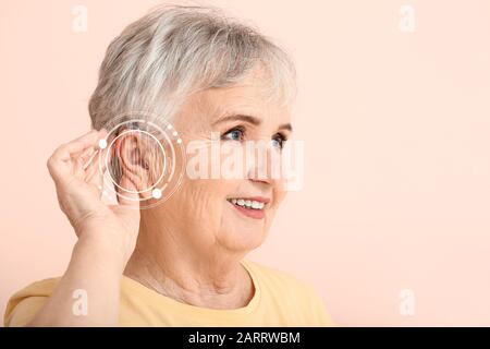 Seniorin mit Hörgerät auf Farbhintergrund Stockfoto