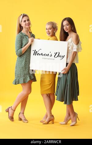 Schöne junge Mädchen halten Plakat mit Text FRAUENTAG auf Farbhintergrund Stockfoto