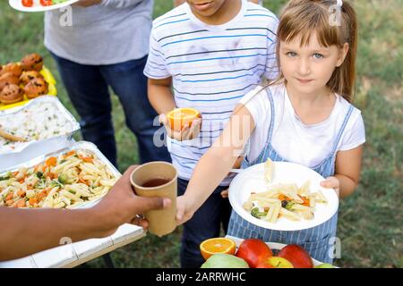 Freiwillige geben Essen an arme kleine Mädchen im Freien Stockfoto