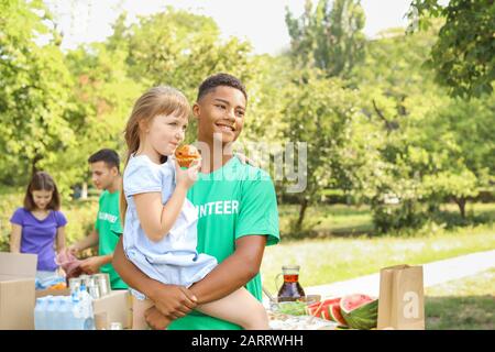 Afrikaner - Freiwilliger mit arme kleine Mädchen im Freien Stockfoto