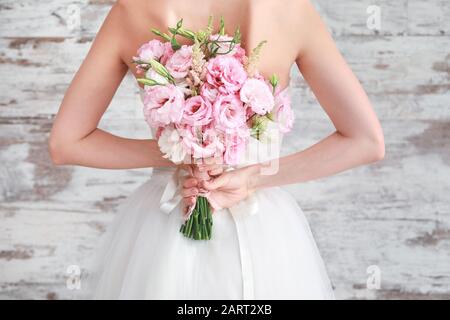 Schöne junge Frau mit Hochzeitstrauß auf Holzhintergrund, Rückansicht Stockfoto