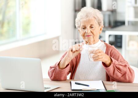 Ältere Frau, die zu Hause Medikamente nimmt Stockfoto