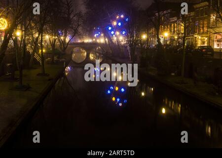 In Utrechter, Niederlande, 21. Januar 2020. Doppelbogensteinbrücke über den Kanal im Zentrum von Utrechter. Nebliger Abend, Blick auf den Kanal, Häuser Stockfoto