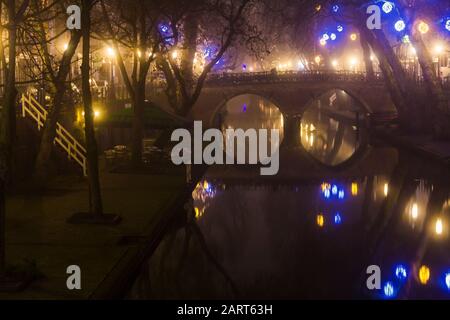 In Utrechter, Niederlande, 21. Januar 2020. Doppelbogensteinbrücke über den Kanal im Zentrum von Utrechter. Nebliger Abend, Blick auf den Kanal, Häuser Stockfoto