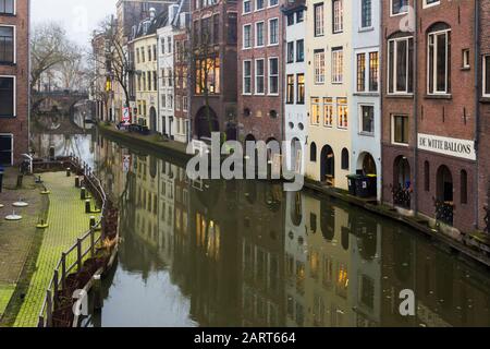 In Utrechter, Niederlande, 21. Januar 2020. Doppelbogensteinbrücke über den Kanal im Zentrum von Utrechter. Nebliger Abend, Blick auf den Kanal, Häuser Stockfoto