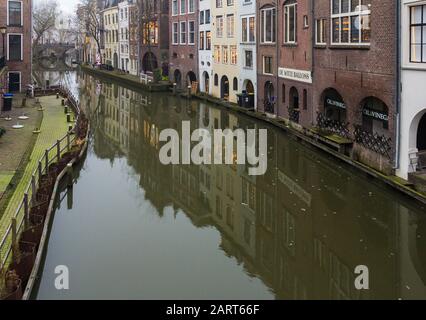 In Utrechter, Niederlande, 21. Januar 2020. Doppelbogensteinbrücke über den Kanal im Zentrum von Utrechter. Nebliger Abend, Blick auf den Kanal, Häuser Stockfoto