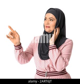 Schöne reife Muslimin, die etwas auf weißem Hintergrund zeigt Stockfoto