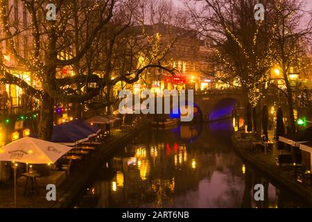 In Utrechter, Niederlande, 21. Januar 2020. Doppelbogensteinbrücke über den Kanal im Zentrum von Utrechter. Nebliger Abend, Blick auf den Kanal, Häuser Stockfoto