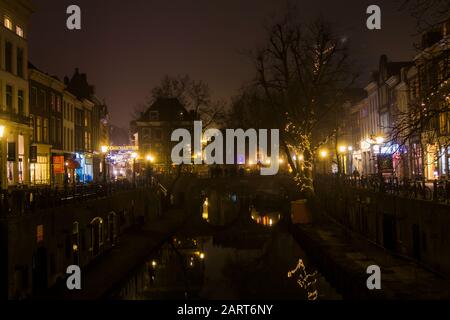 In Utrechter, Niederlande, 21. Januar 2020. Doppelbogensteinbrücke über den Kanal im Zentrum von Utrechter. Nebliger Abend, Blick auf den Kanal, Häuser Stockfoto